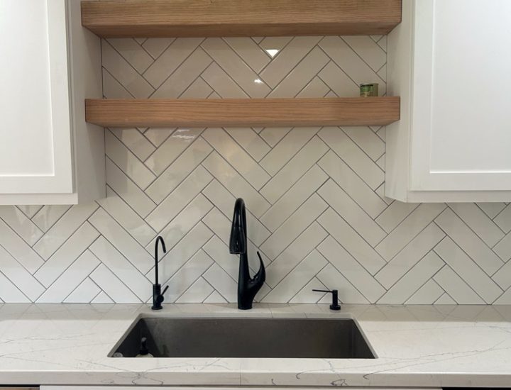Chevron tile backsplash installed in the kitchen with wall mounted wood shelves in between cabinets