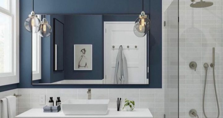 A remodeled bathroom with a shower area having a glass partition, a storage cabinet with sink on top, and a tiled backsplash and flooring